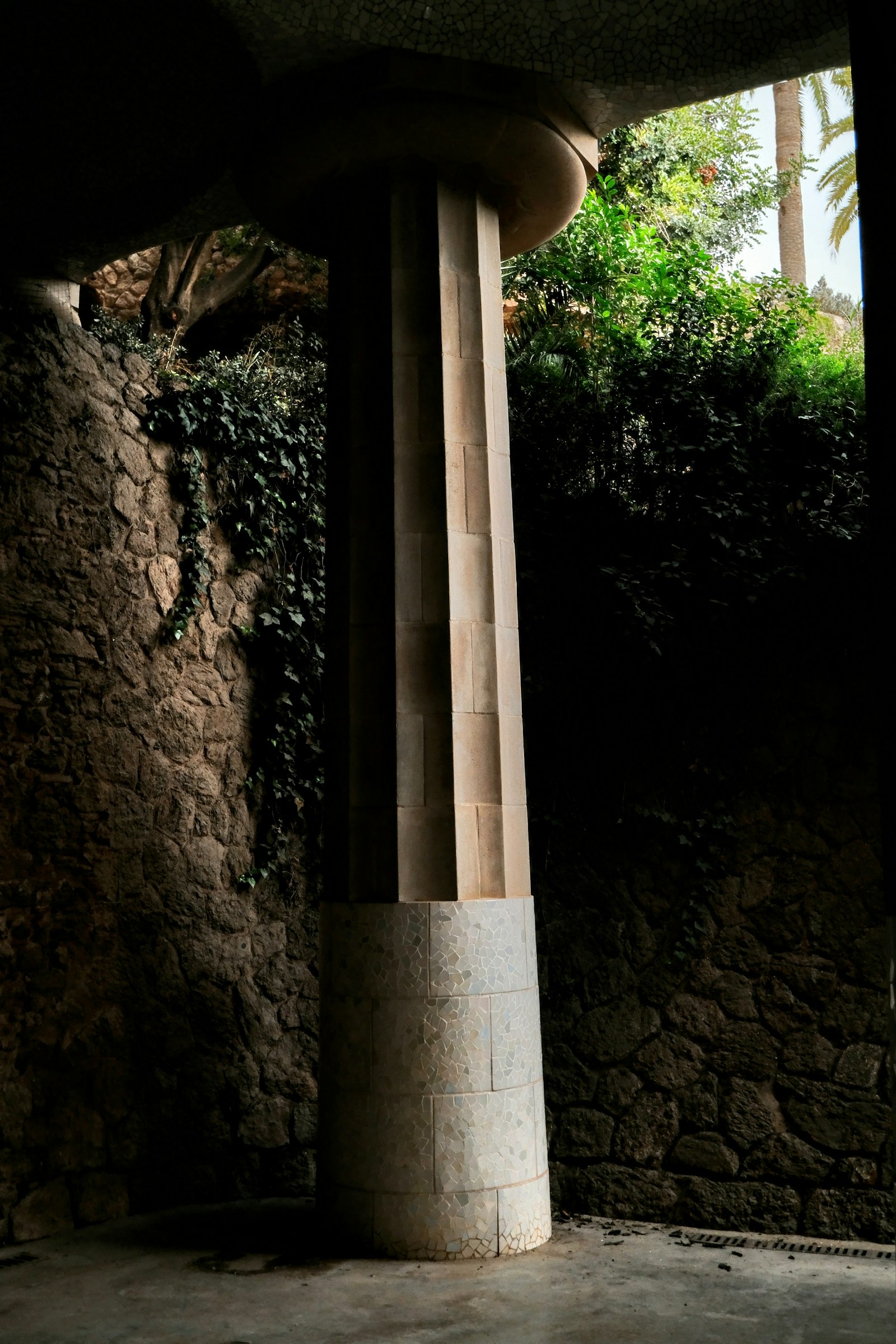 A tall stone pillar standing next to a stone wall